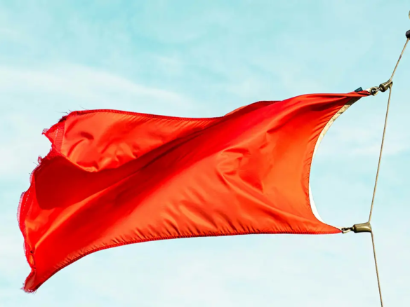 An image of a red flag waving in the wind.